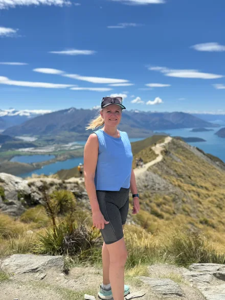 Lene på fjelltur med utsikt over fjell og vann.