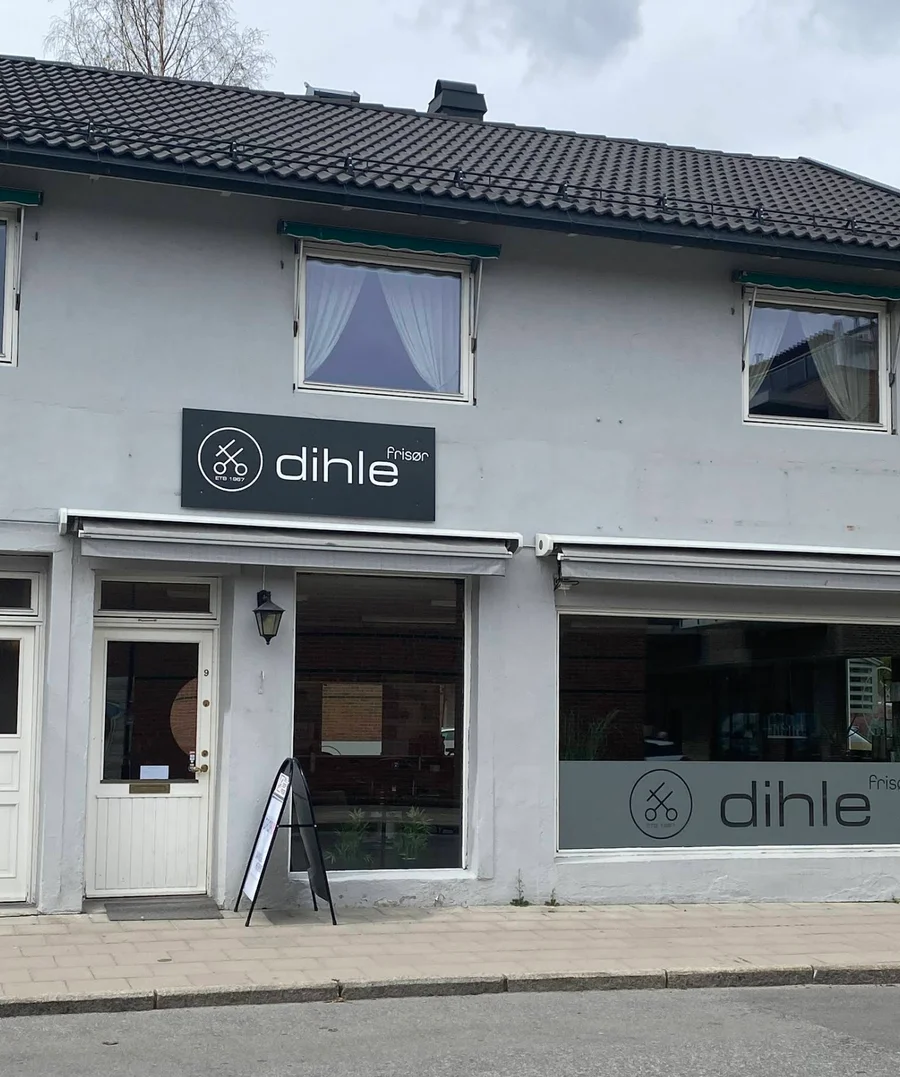 Fasaden til Dihle frisør med hvit inngangsdør, store vinduer og svart skilt med salongens navn.